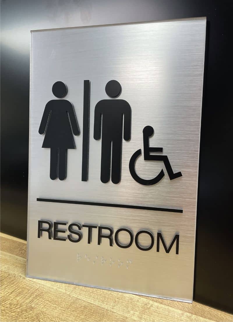 Restroom sign with male, female, and wheelchair symbols for accessibility.