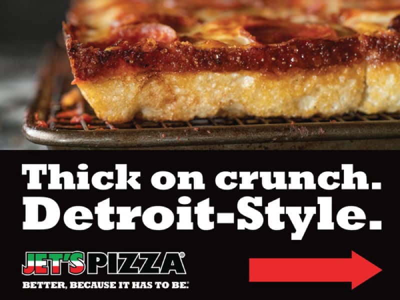 Close-up of Detroit-style pizza with thick crust and toppings.