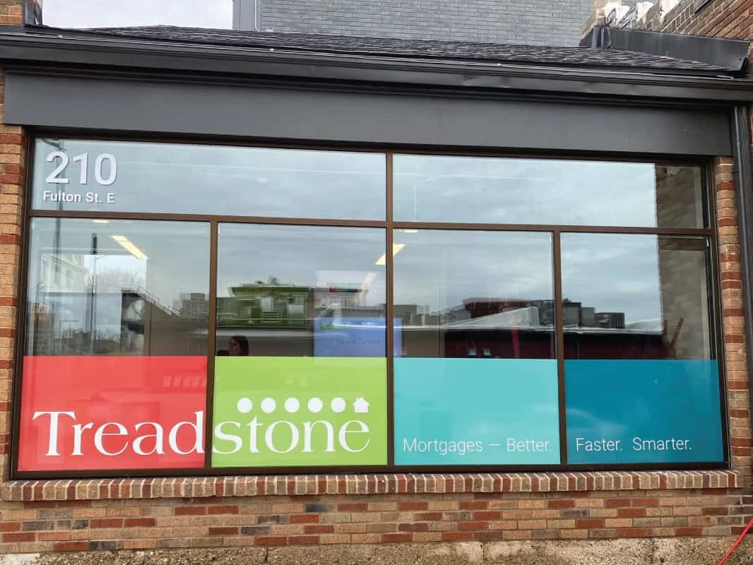 Storefront window with colorful signs including Treadstone and mortgage ads.