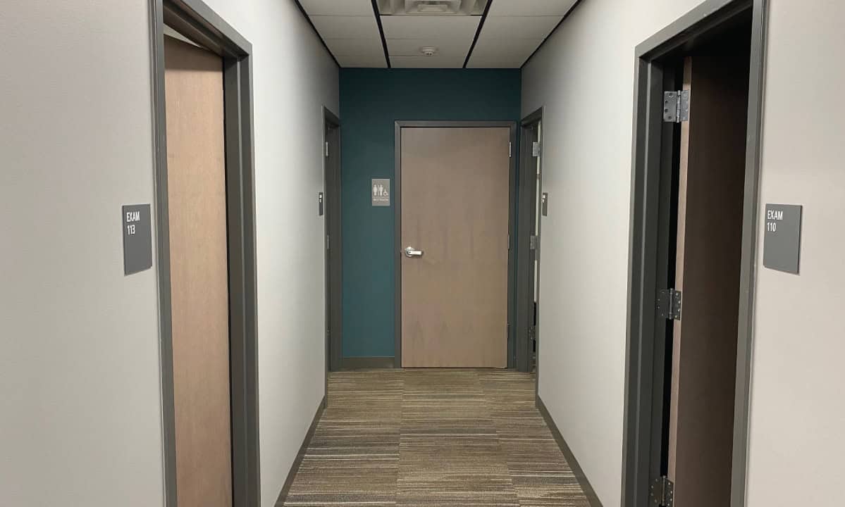 Hallway with two elevator doors and a door at the end, handicap signs visible.