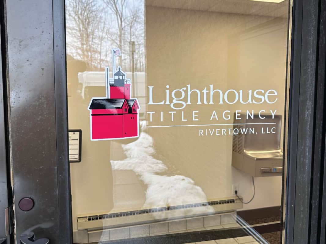 Lighthouse Title Agency logo on glass door with lighthouse graphic.