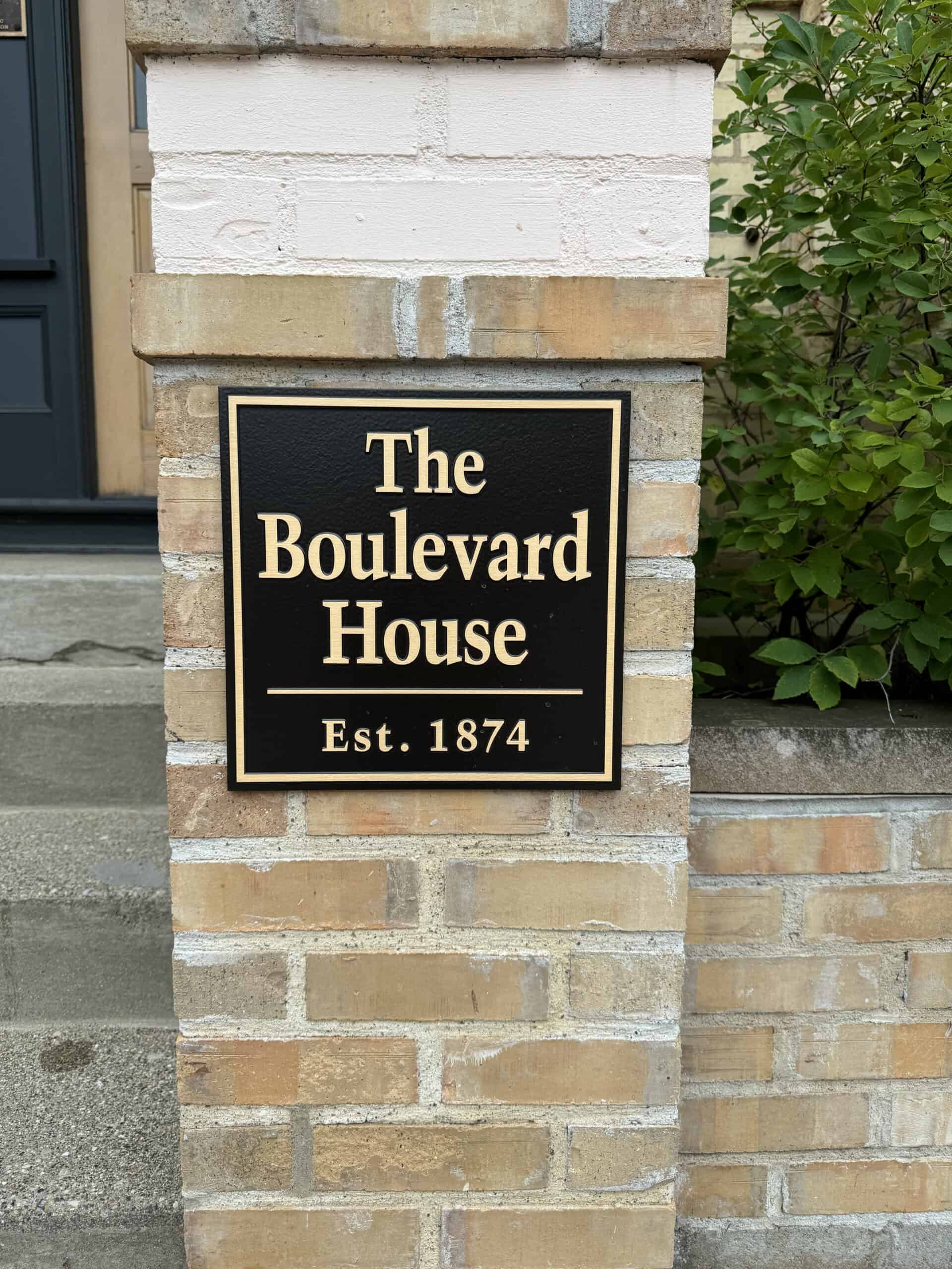 Black and gold sign reading 'The Boulevard House Est. 1874' on brick wall.