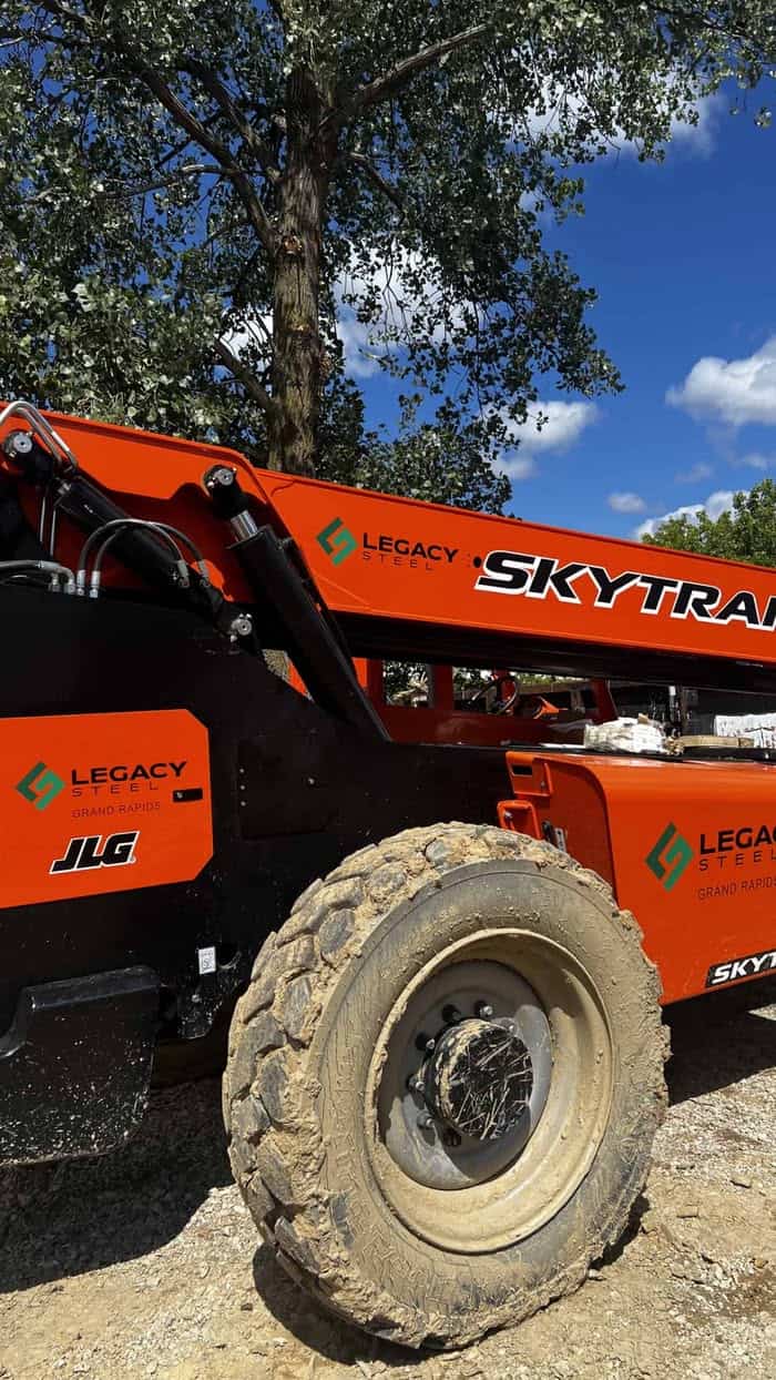 Orange SkyTrak telehandler with large tires and boom arm in outdoor setting.