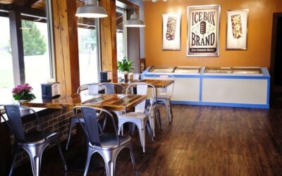 Cozy ice cream shop with wooden floors, metal chairs, and Ice Box Brand signage.