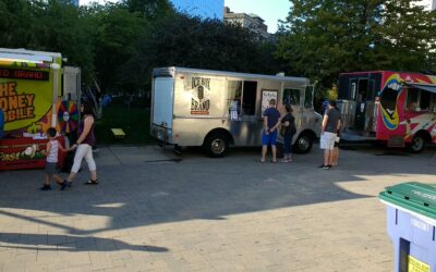 Ice Box Brand ice cream trucks with people in line and children nearby.