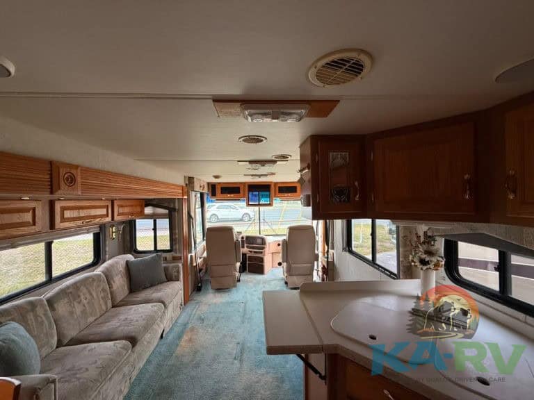 RV interior with cozy seating, kitchen, and large windows for scenic views during travel.