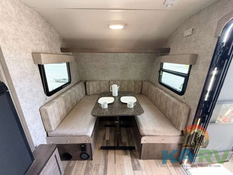 RV dining area with U-shaped seating and table inside a Winnebago Winnie Drop 1780.