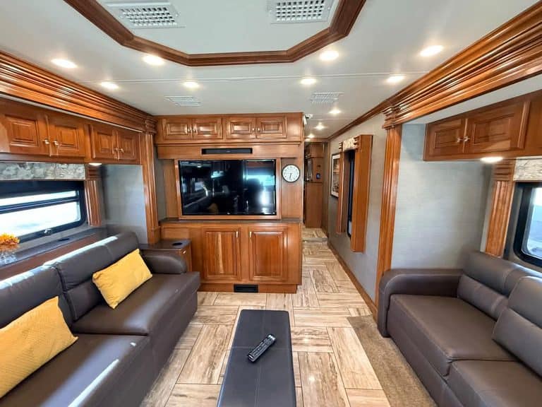 Spacious RV living room with leather sofas and wooden cabinetry.