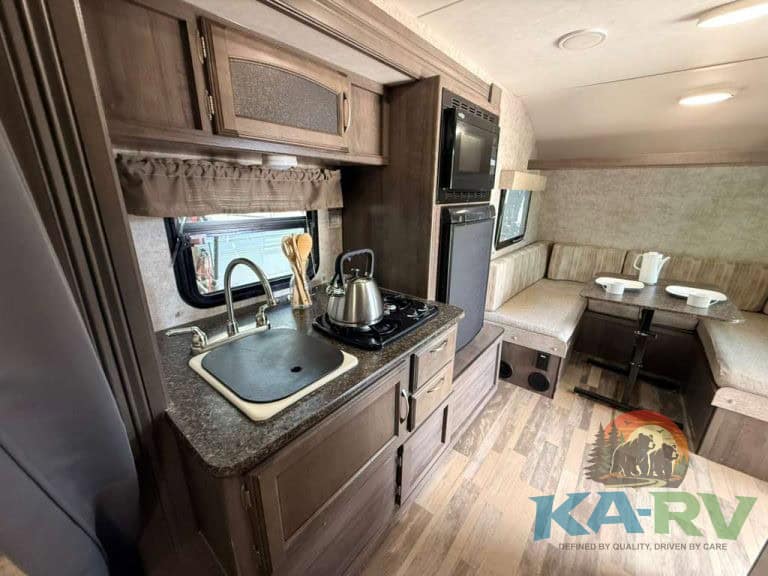 Compact RV kitchen and dining area in a 2017 Winnebago Winnie Drop.