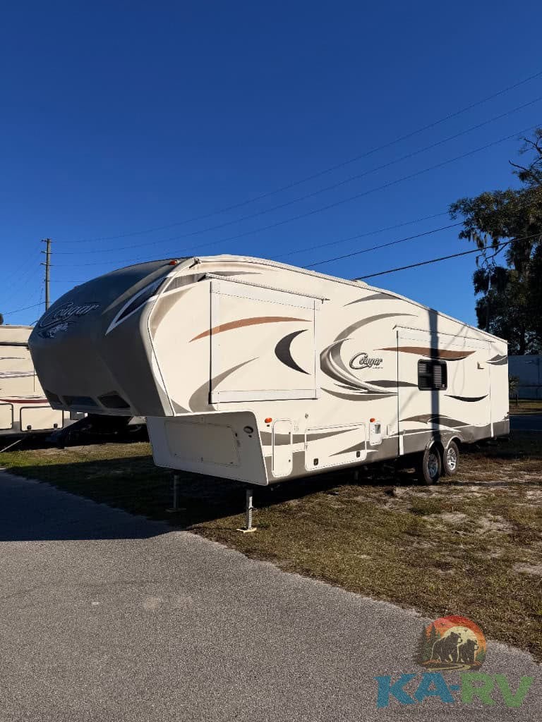 2014 Keystone Cougar 331MKS travel trailer parked outdoors under clear blue sky.