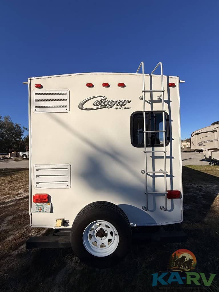 White Keystone Cougar RV rear view with ladder and branding.