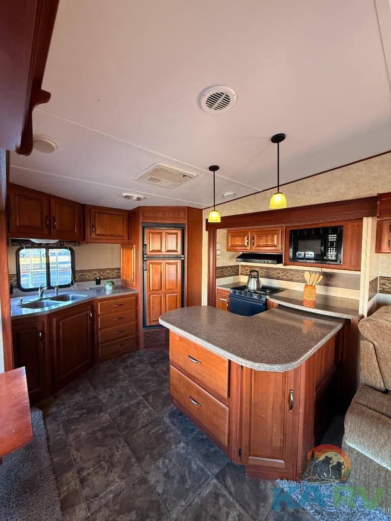 RV kitchen interior with wooden cabinetry and modern appliances.