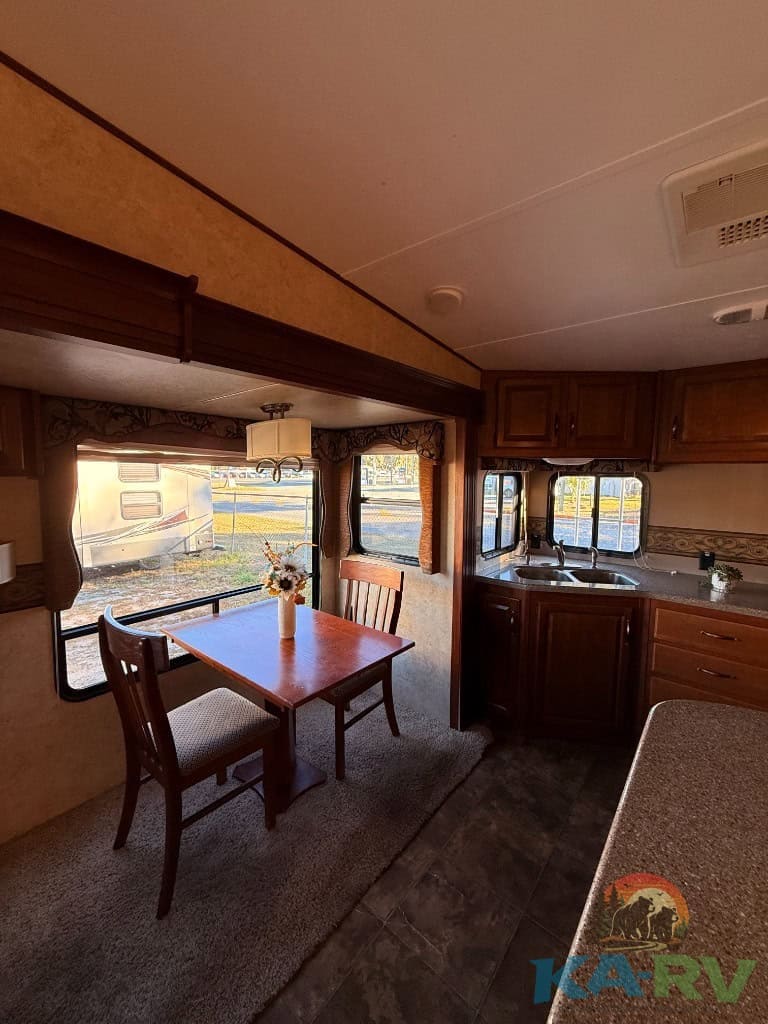 Interior view of a dining area inside a 2014 Keystone Cougar 331MKS RV, showcasing a cozy space with.