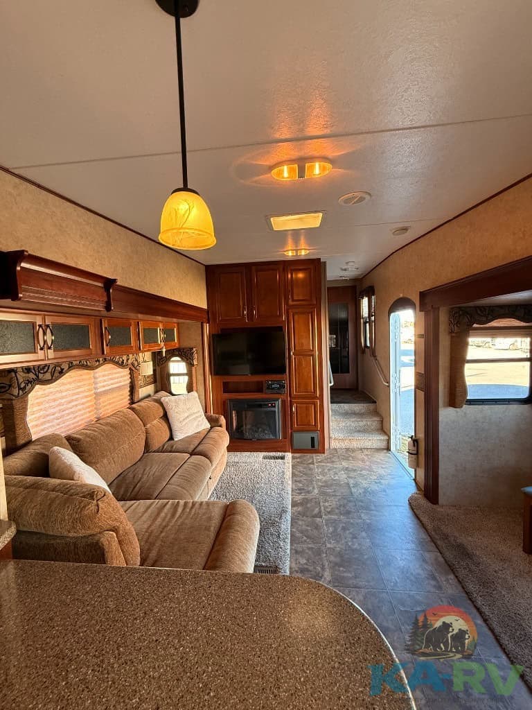 RV interior living space featuring comfortable sofas, wooden cabinetry, and a built-in TV for relaxa.