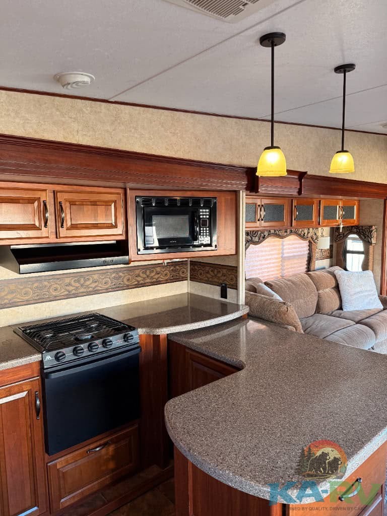 Modern RV kitchen with stove, microwave, and cozy seating area.