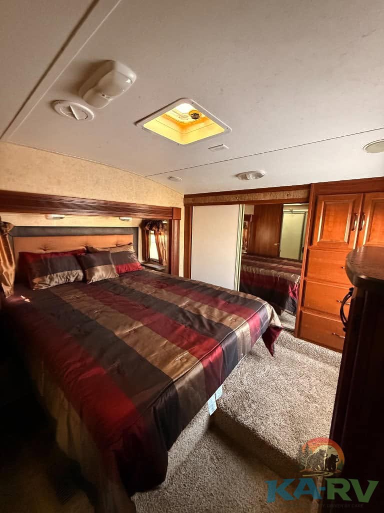 Interior of a 2014 Keystone Cougar 331MKS RV bedroom with wooden cabinetry and bed linens.