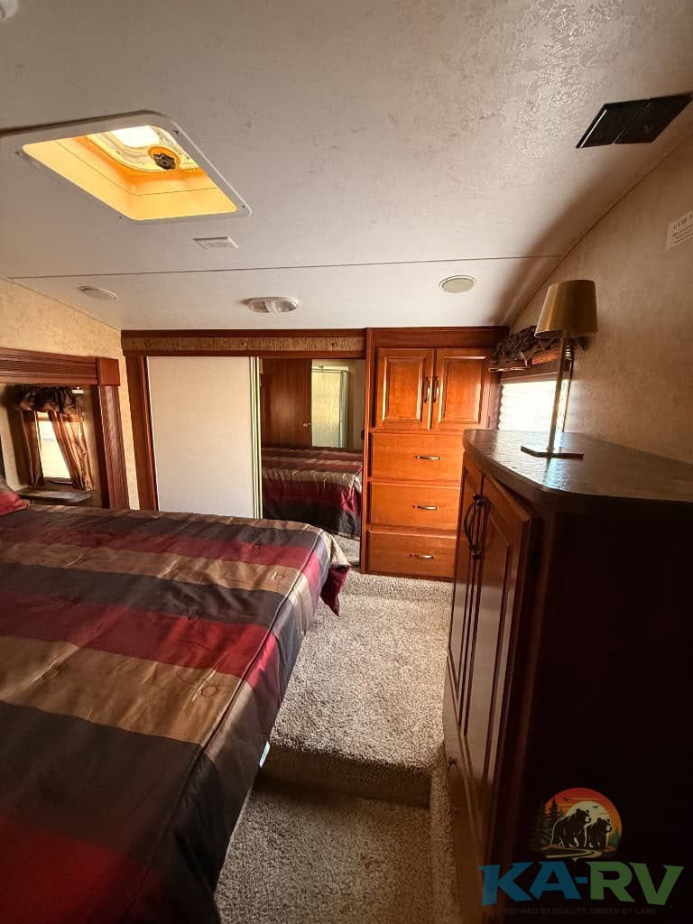 Comfortable RV bedroom interior with wooden cabinets and mirror closet.