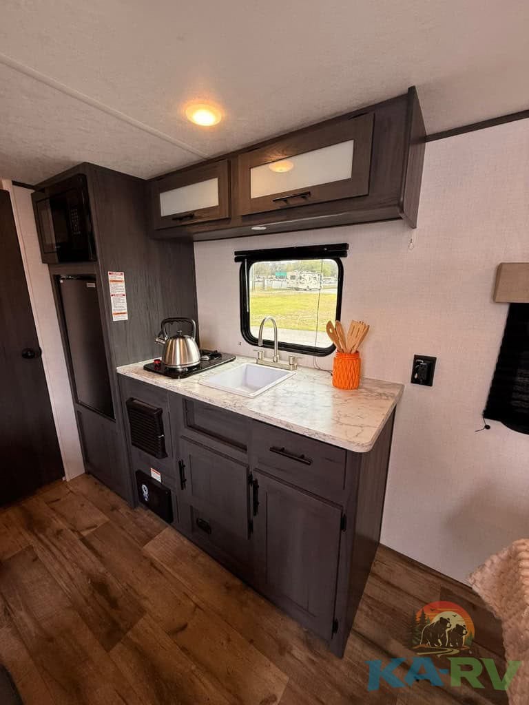 Compact RV kitchen with sink, microwave, and storage.