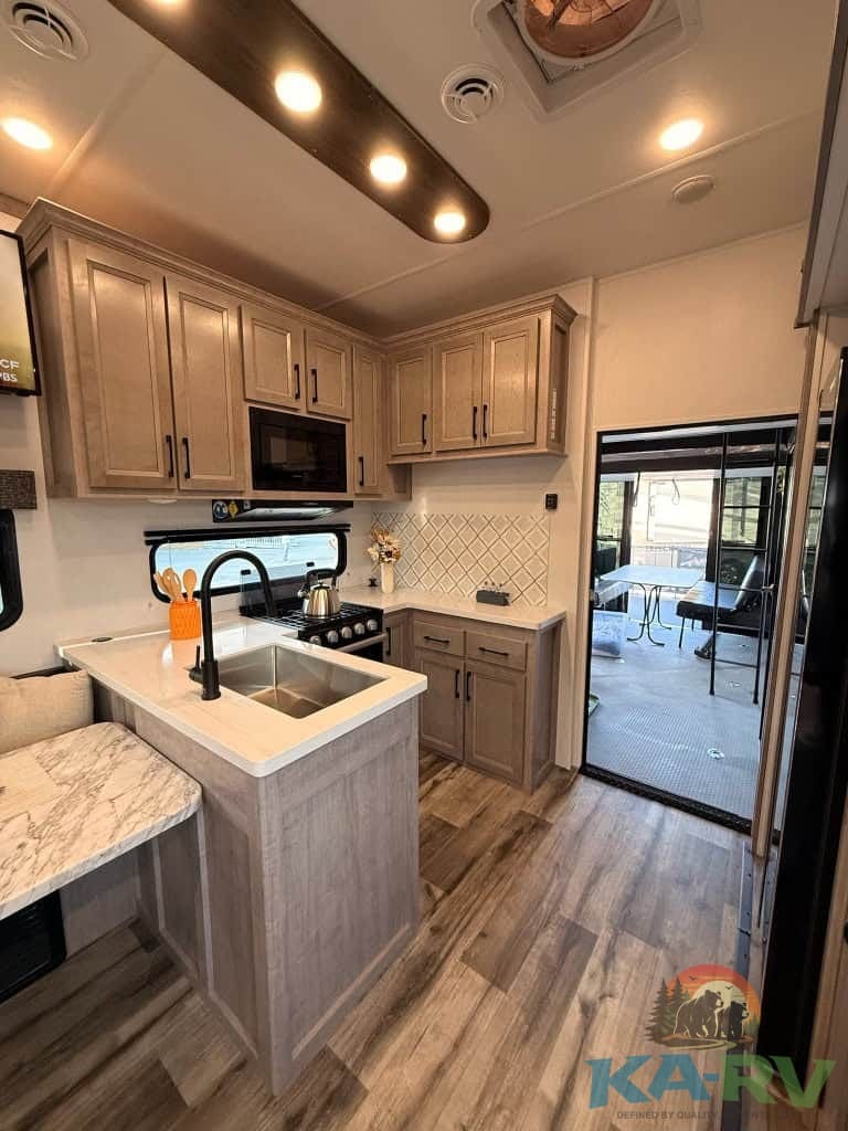 RV kitchen with wooden cabinets, stainless steel sink, and modern appliances for optimal RV living.