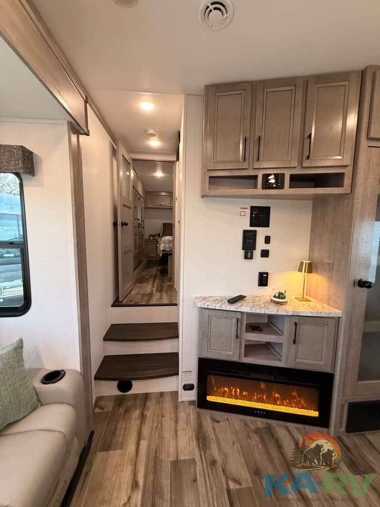 Electric fireplace and modern cabinetry in RV interior.