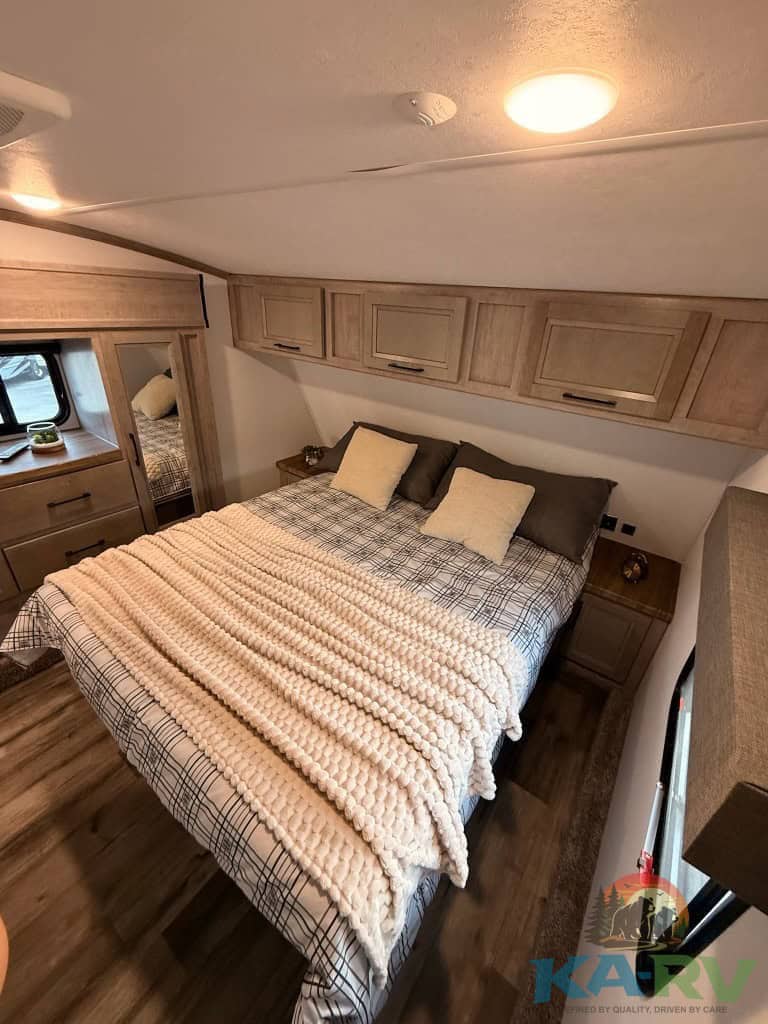RV bedroom with cozy bed, storage cabinets, and modern decor for optimal comfort.
