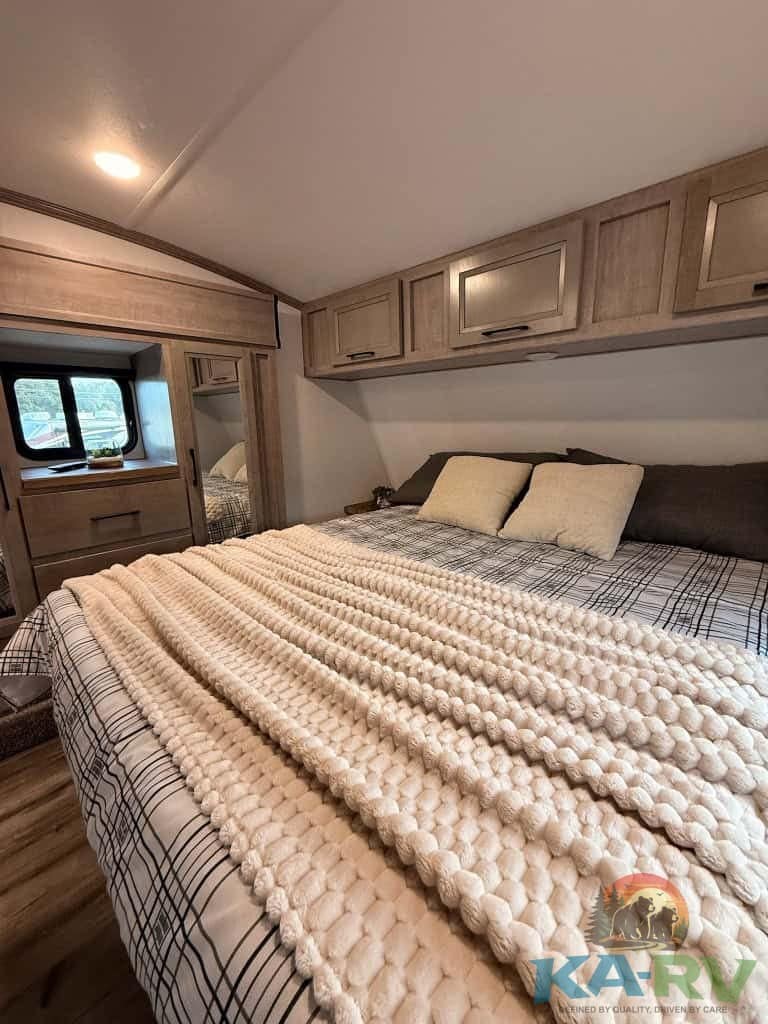 Interior of RV bedroom with storage cabinets and cozy bed for travel comfort.