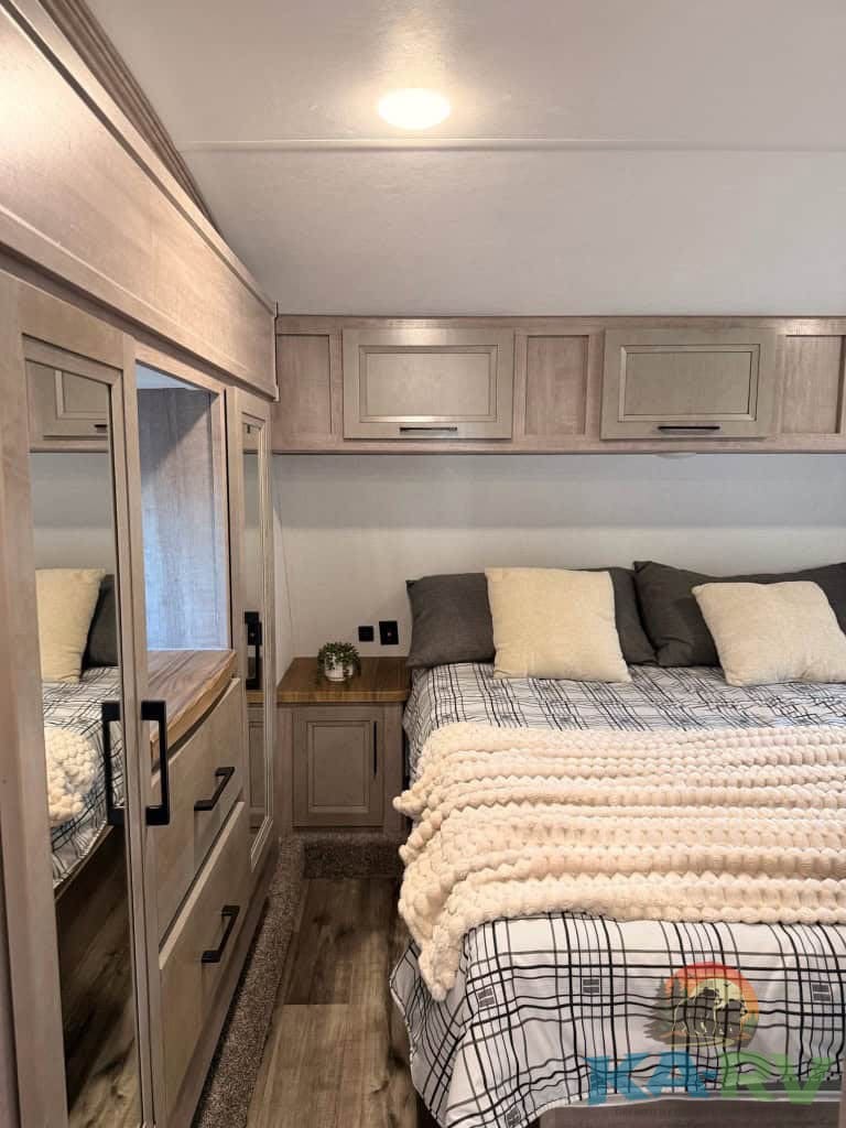 Interior view of a 2025 Dutchmen Voltage RV bedroom with modern cabinetry and cozy bedding.