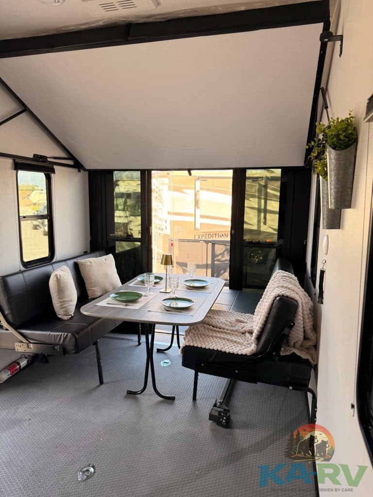 RV interior with dining space, large windows, and cozy seating for travel comfort.