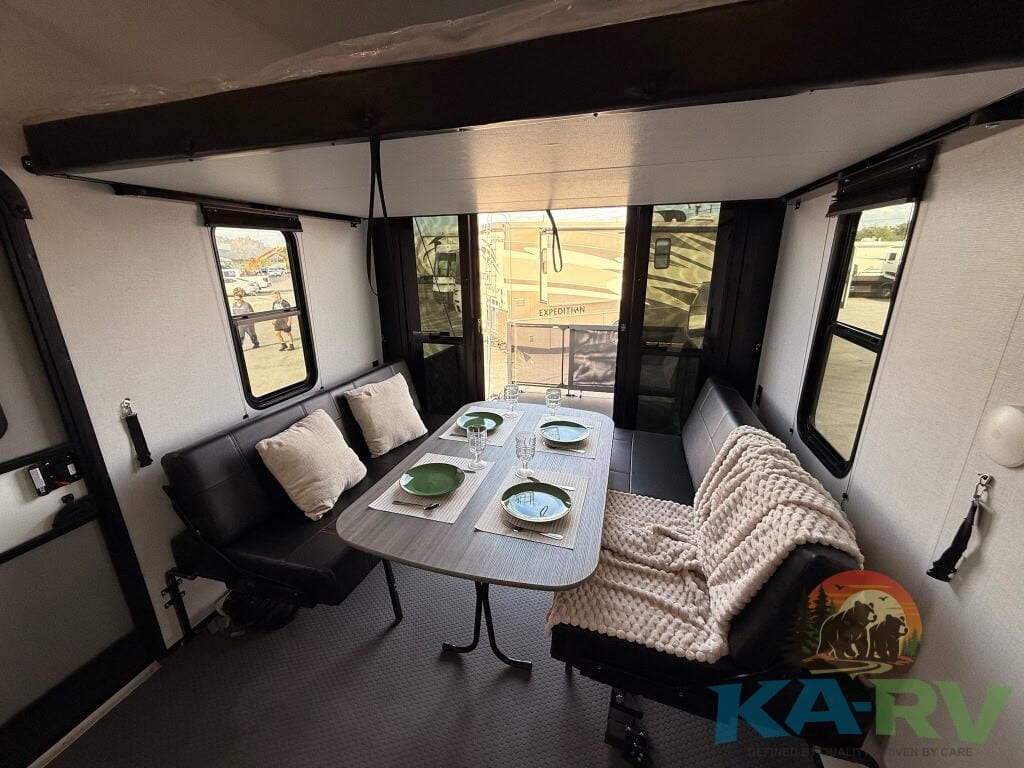 Interior view of the 2025 Dutchmen Voltage RV showing a cozy dining area with seating and table.