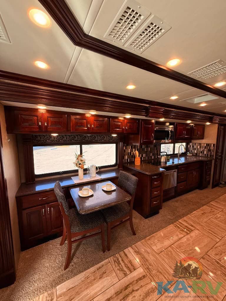 Luxury RV kitchen with dark wood cabinets and modern appliances.