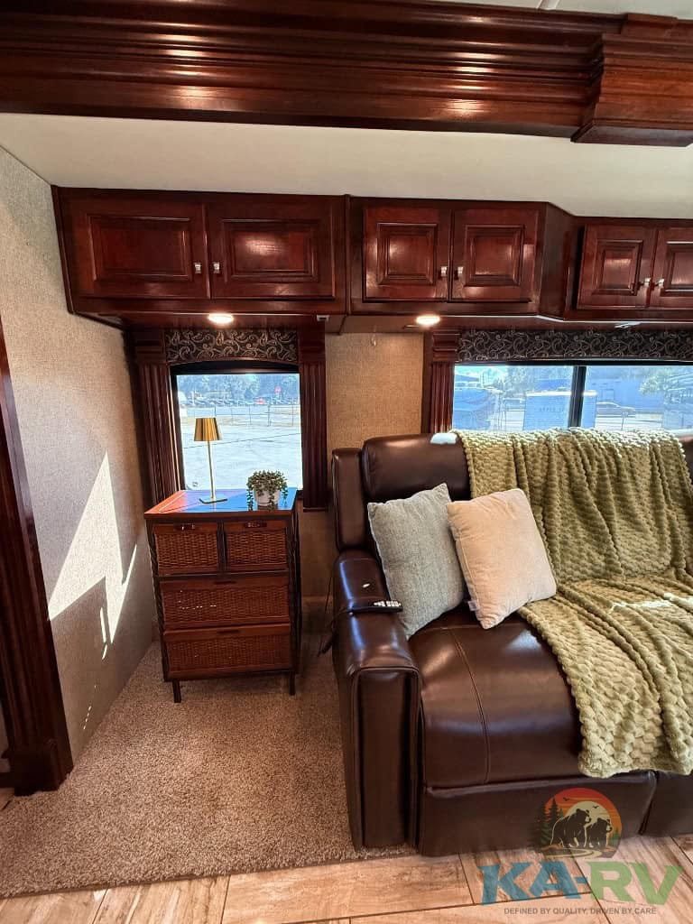 Interior view of a luxury RV with wooden cabinetry and cozy seating.