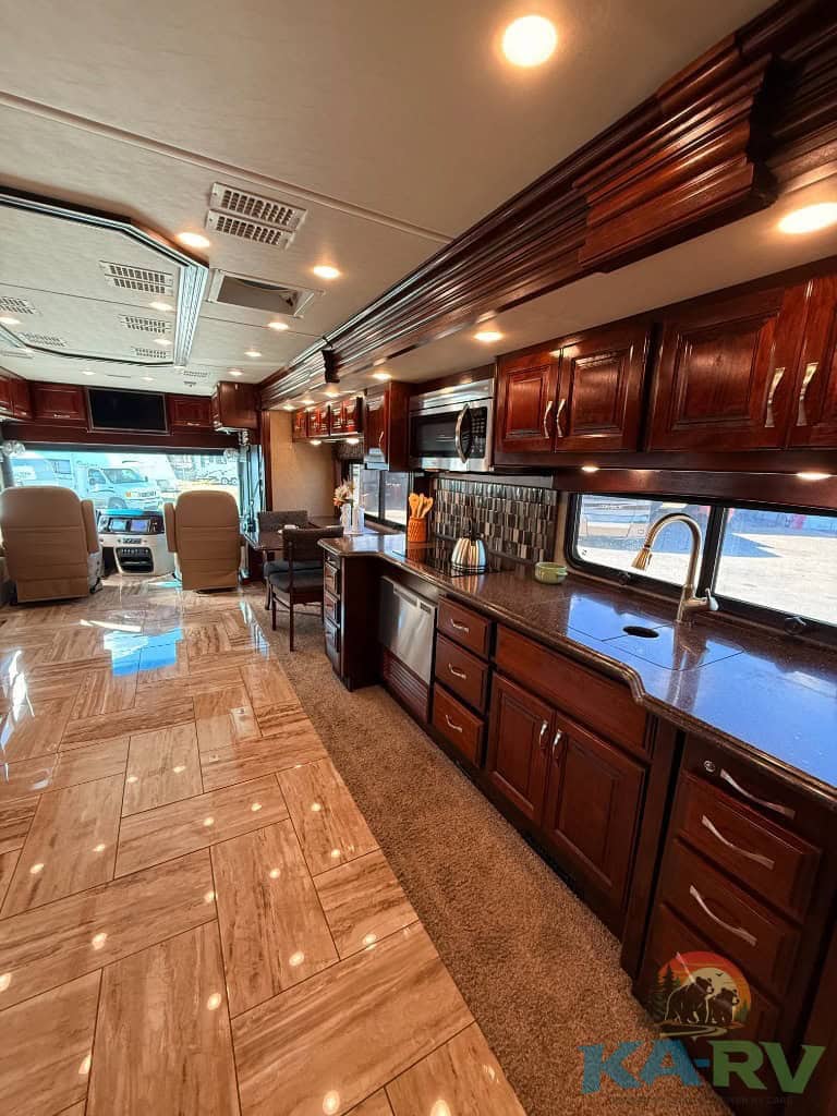 RV kitchen with wooden cabinets, microwave, and sink for travel comfort.