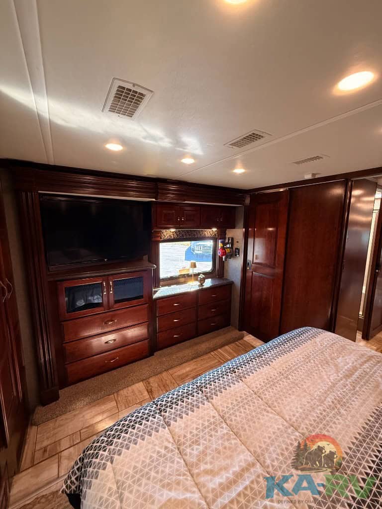 RV bedroom interior with custom wood cabinets and cozy bedding.
