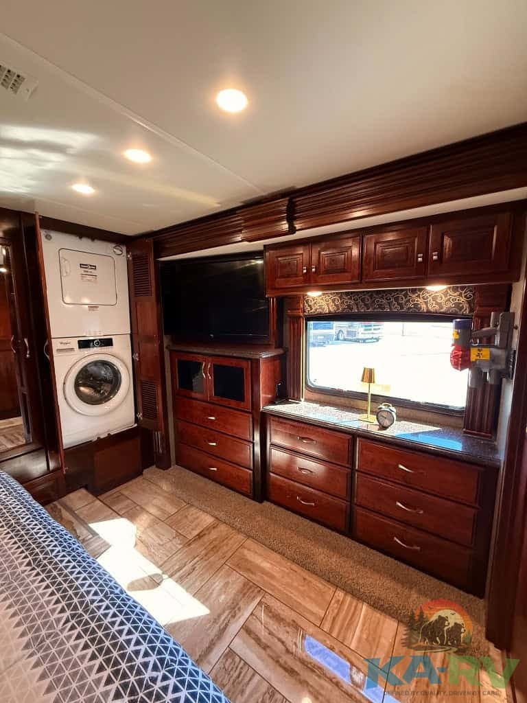 RV interior with wooden cabinets, washer/dryer, and large window in a 2018 Fleetwood Discovery 39F.