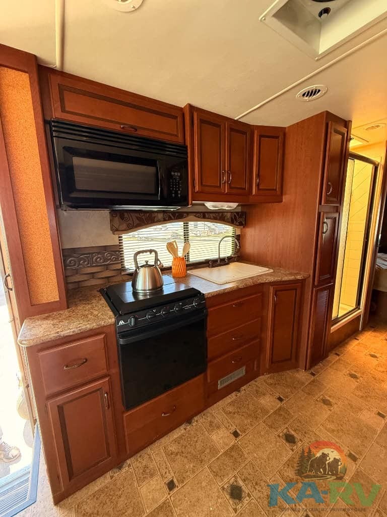 Affordable RV kitchen with stove, microwave, and cabinetry.