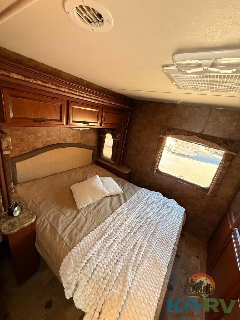 Accessible RV bedroom with cozy bed and storage cabinets.