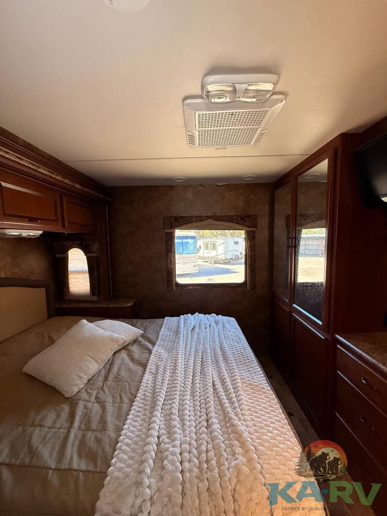 RV bedroom interior with storage cabinets, window view, and ceiling vent in a 2013 Four Winds Hurric.