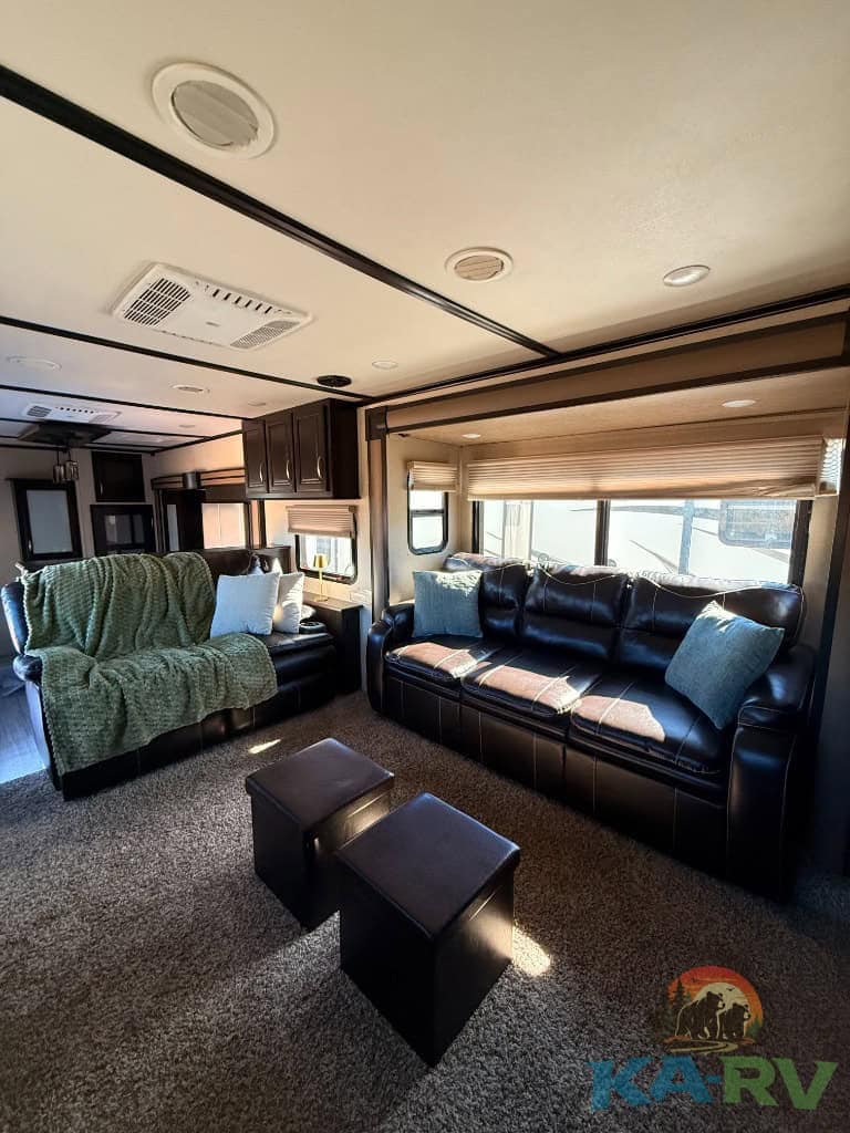 Comfortable RV living room with leather sofas and large windows.
