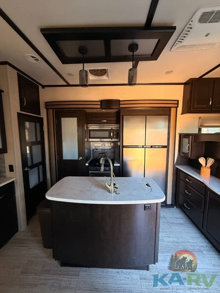 Stylish RV kitchen featuring dark cabinets, stainless appliances, and a central island.