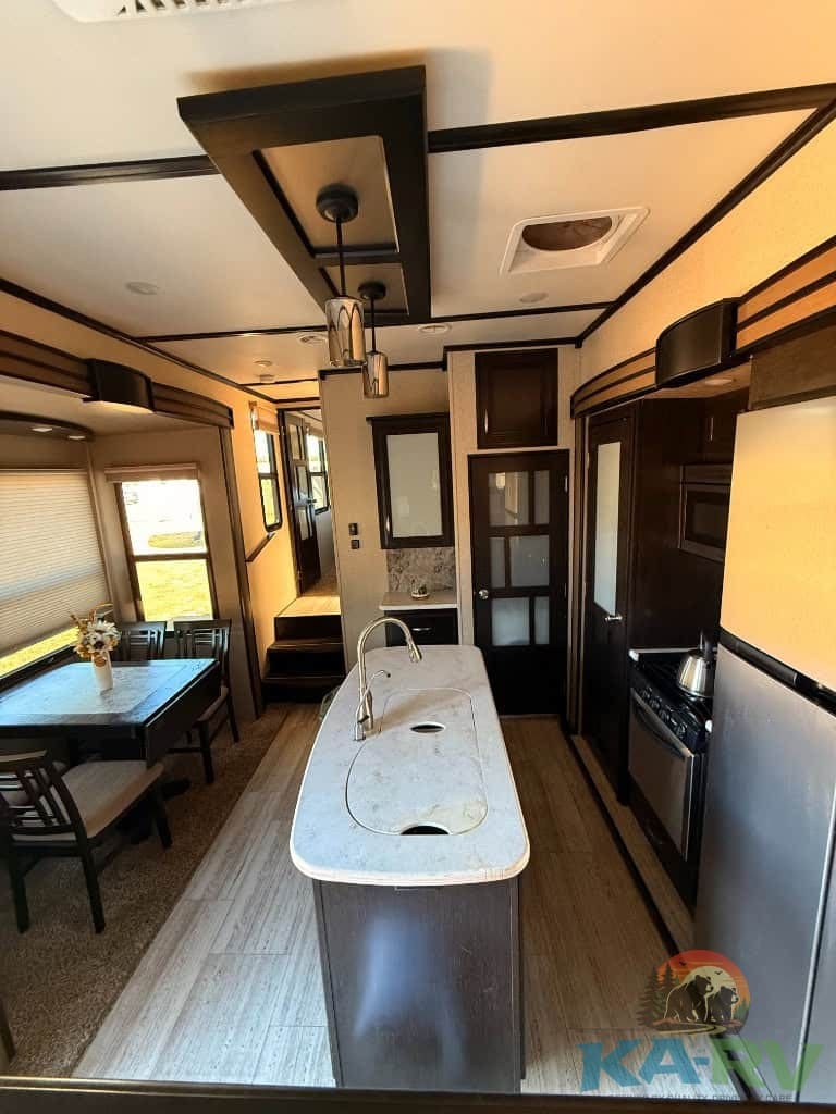 RV kitchen with island and dining table in a Grand Design Momentum 376TH.