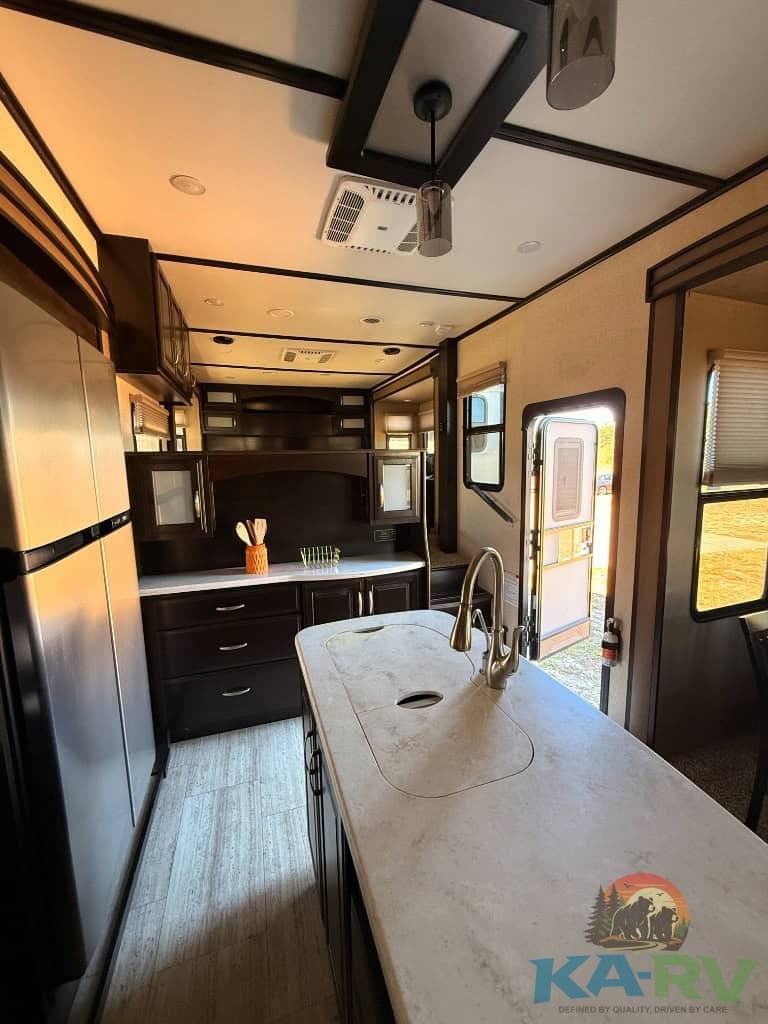 RV kitchen with dark cabinets, large countertop, and modern appliances for optimal travel comfort.