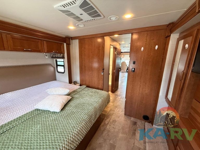 RV bedroom interior with wooden cabinetry and a large bed.