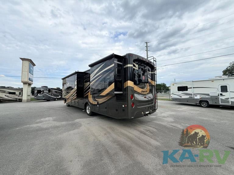 Luxury RV motorhome with black and gold exterior, parked outdoors at Karv Repair.