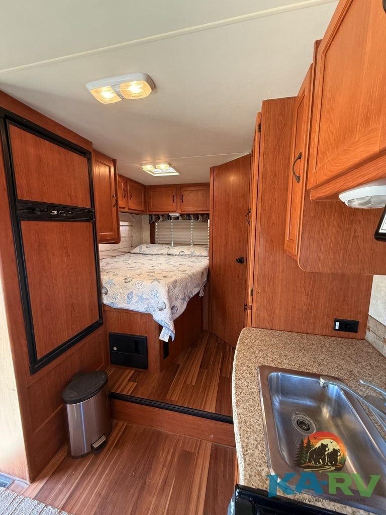 Interior view of a 2013 Coachmen Freelander 23CB RV showing kitchen and sleeping area.