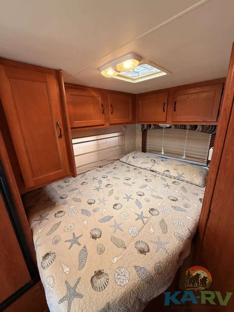 Cozy RV bedroom with wooden cabinets and starfish-themed bedding.