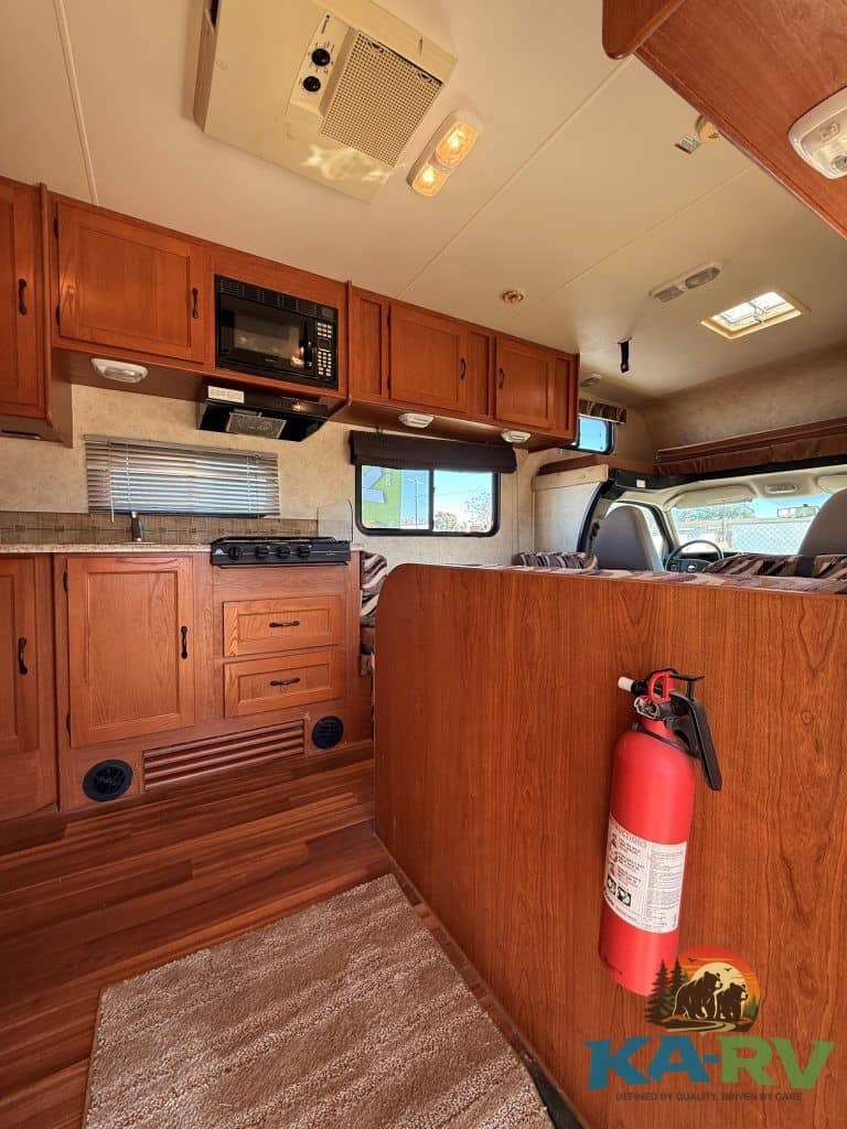 Interior of a 2013 Coachmen Freelander 23CB RV with wood cabinets and cozy living space.