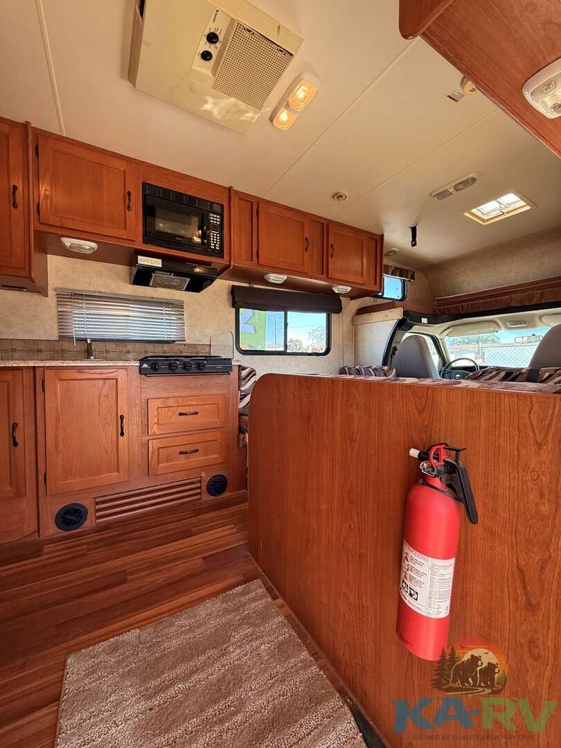 Interior of a 2013 Coachmen Freelander 23CB RV with wood cabinets and cozy living space.