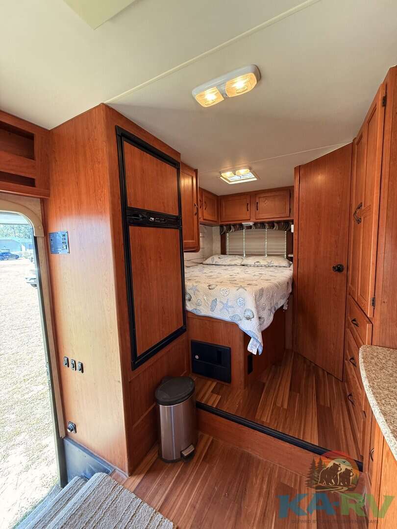 Accessible RV interior with cozy sleeping area and wooden cabinetry.