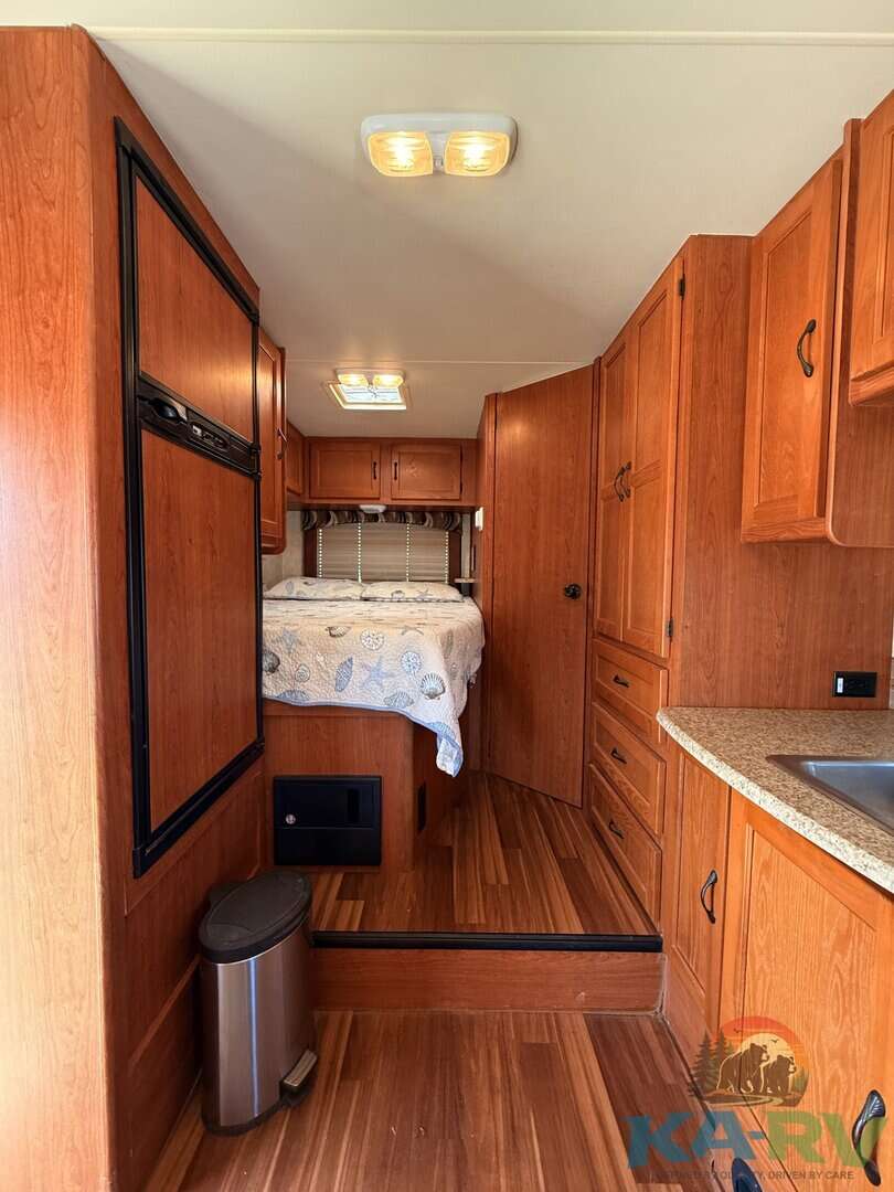 Interior view of a 2013 Coachmen Freelander 23CB RV kitchen and sleeping area.