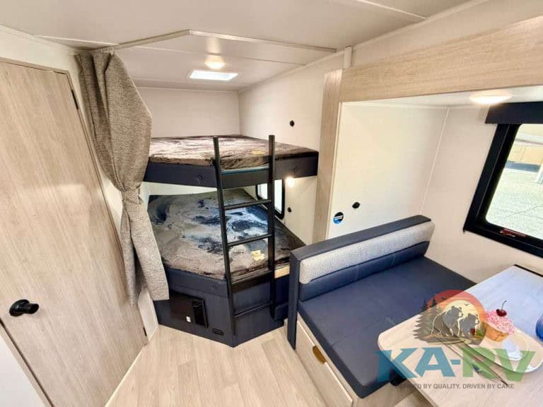 RV interior with bunk beds, sofa, and dining area in 2026 Acclaim 2700BH.